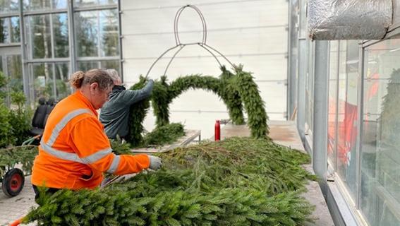 Karin Hida (l.), Mitarbeiterin des Gartenamtes, kümmert sich mit ihren Kollegen um die Kronen der Osterbrunnen. 