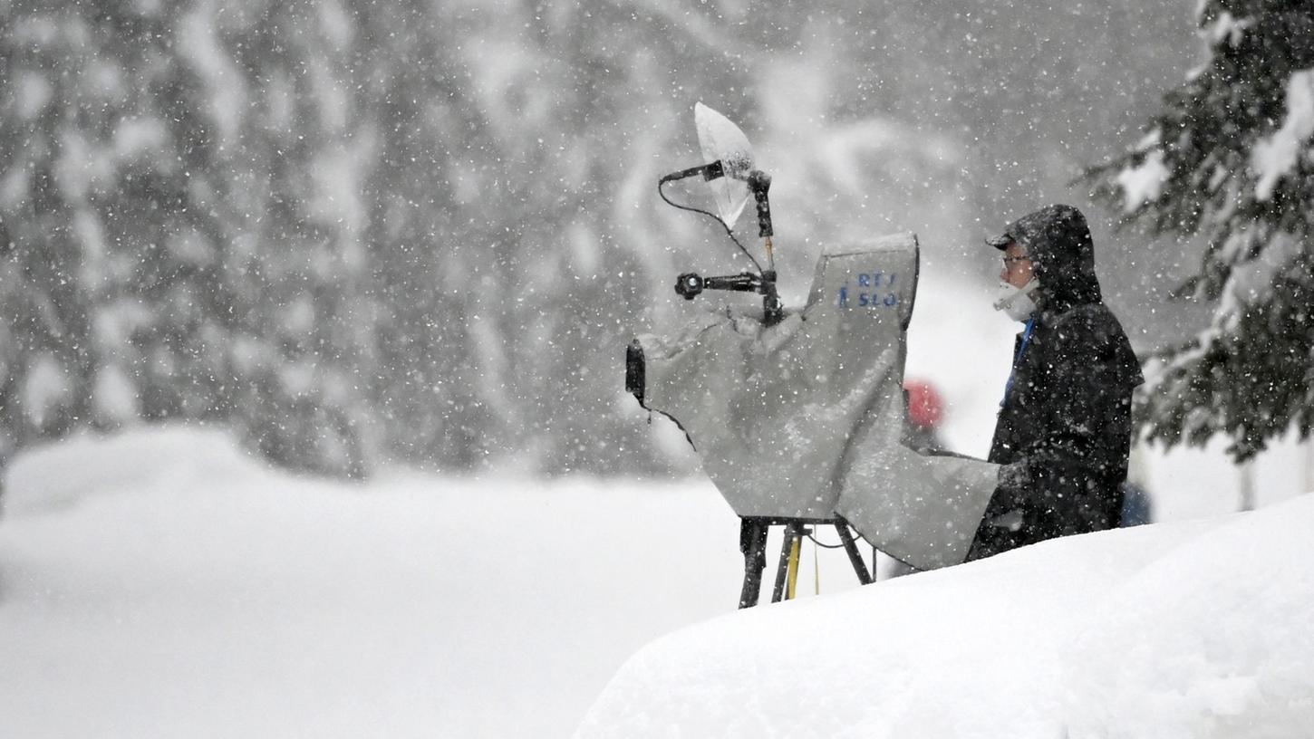 Ein TV-Kameramann steht im Schnee und filmt Wintersport.