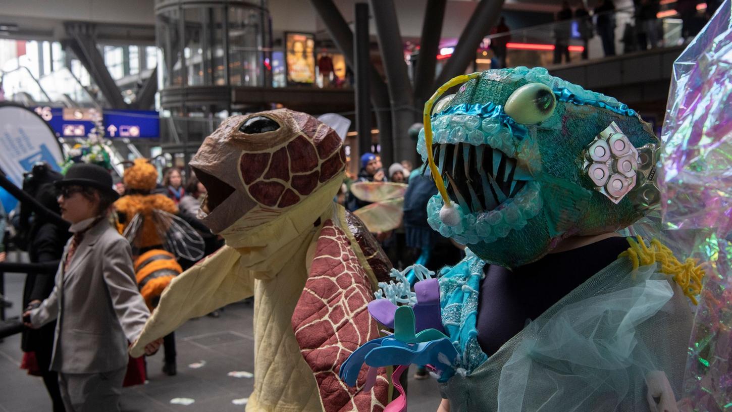 Klima-Aktivisten der Gruppe Extinction Rebellion tragen bei einem Tanz-Flashmob im Berliner Hauptbahnhof fantasievolle Tierkostüme.