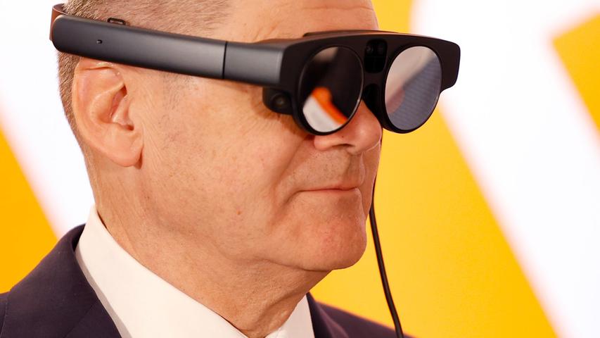 Bundeskanzler Olaf Scholz mit eier AR-Datenbrille (Augmented Reality) zur Prozessüberwachung einer Maschine.