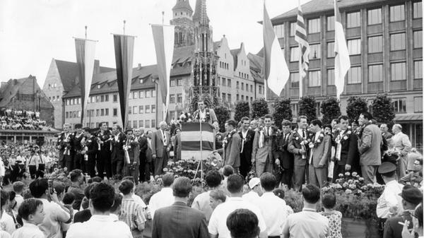 Destination Hauptmarkt: Als die Club-Heroen dort eingetroffen und von kleinen Mädchen mit Blumengirlanden behängt worden waren, hielt Morlock - den Schönen Brunnen und die Sebalduskirche im Rücken - eine kurze Ansprache. Die jungen Spielkameraden rahmen ihr Idol ein.