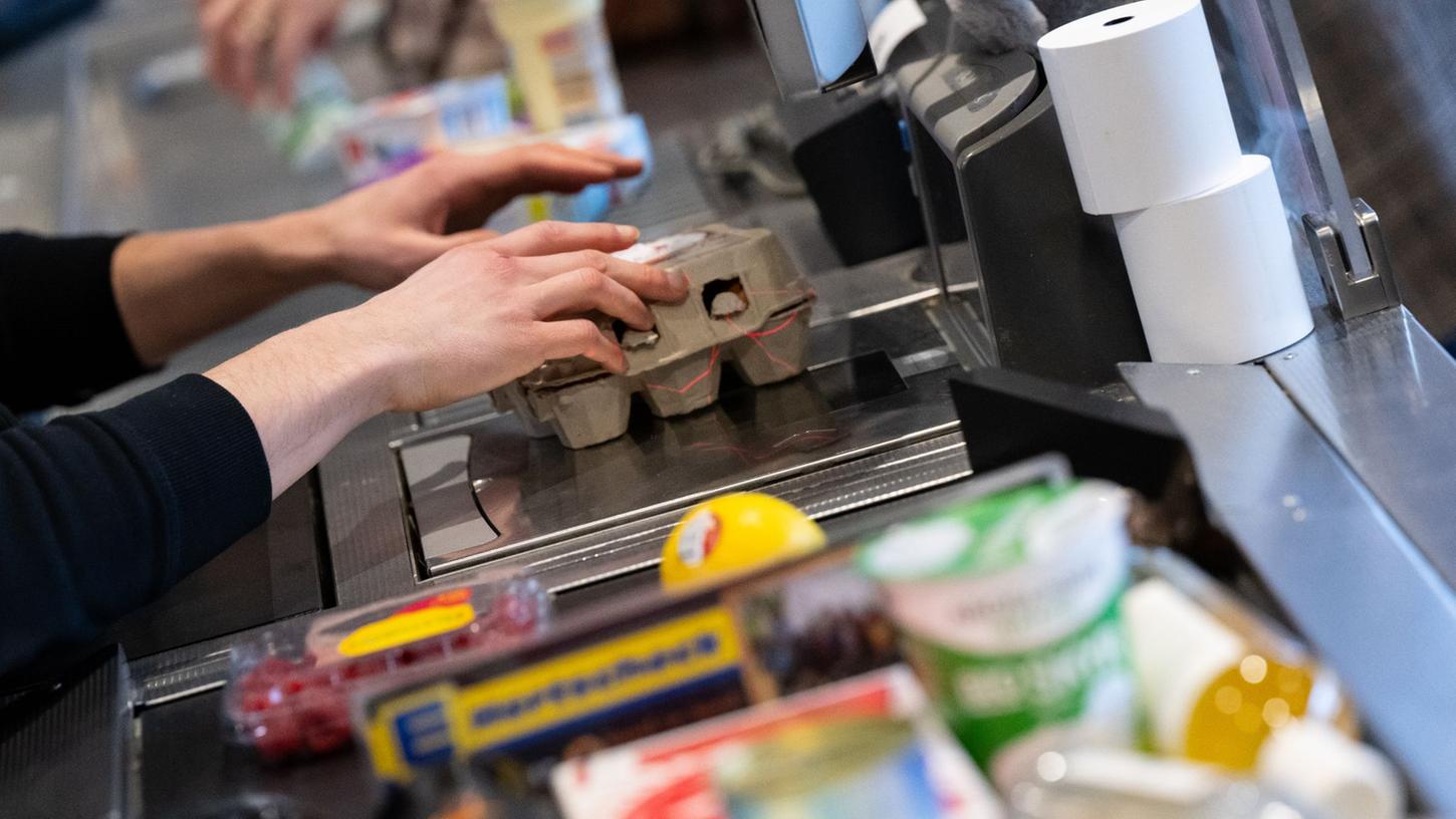 Ein Kassierer scannt in einem Supermarkt an der Kasse die Produkte. (Symbolbild)