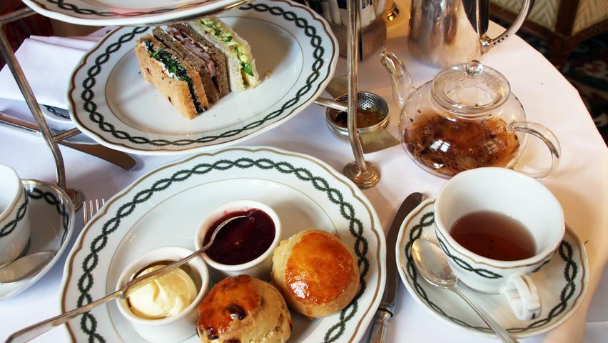Apfel-Zimt-Tee auf eleganten Etageren, dazu Räucherlachs-Sandwiches und Scones mit Erdbeermarmelade.