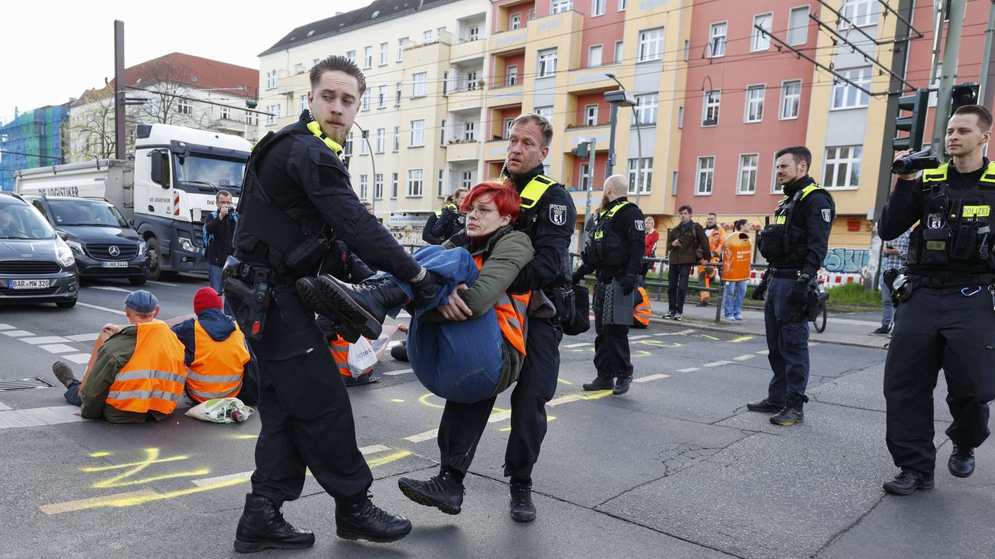 Polizisten tragen eine Aktivistin der Letzen Generation am Montag von der Straßenblockade an der Danziger Strasse weg. 