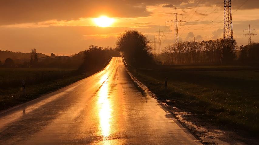 Golden spiegelt sich die Abendsonne auf einer regennassen Straße. Mehr Leserfotos finden Sie hier