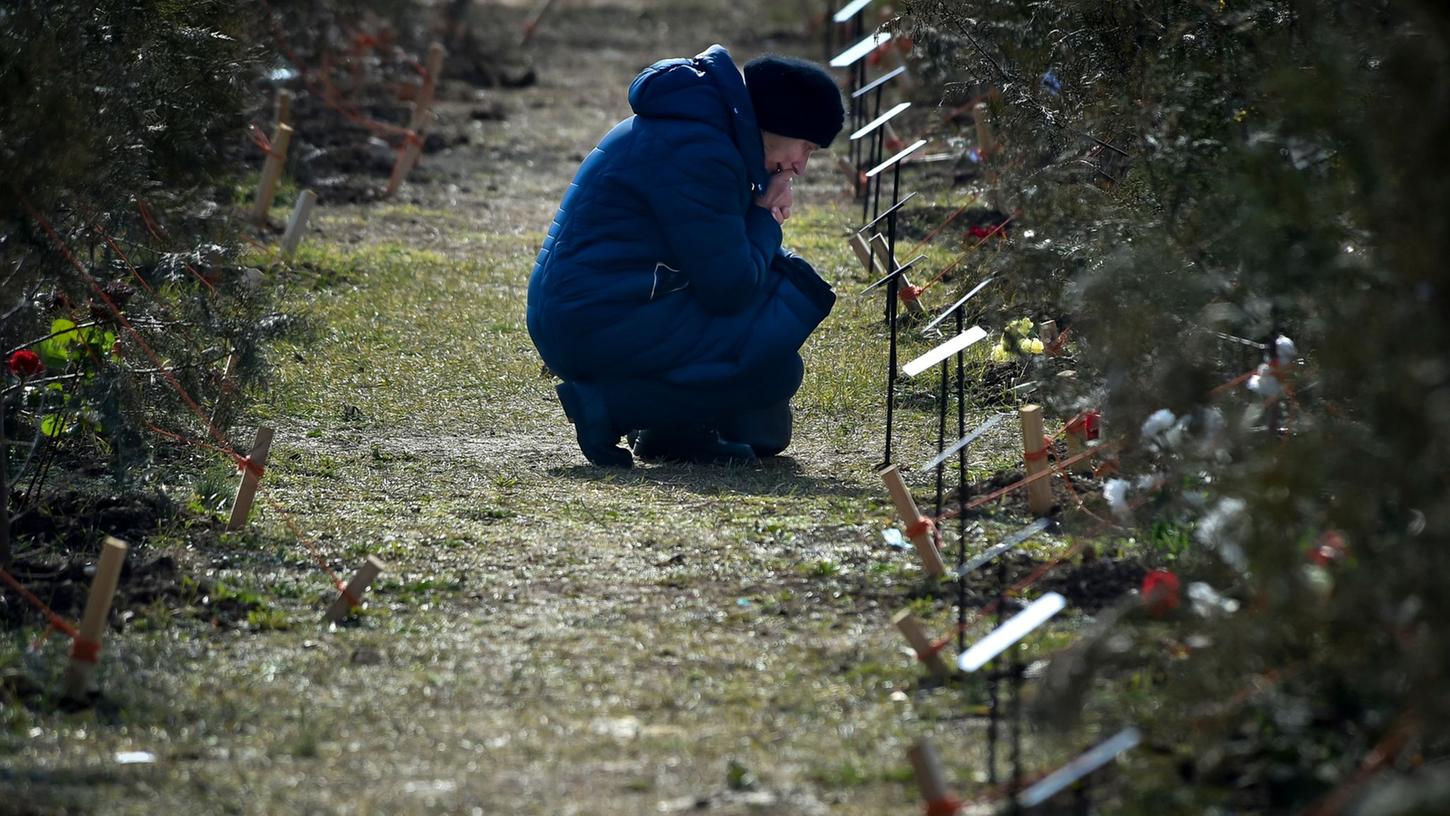 Die Mutter eines russischen Soldaten, der bei einer Militäraktion in der Ukraine getötet wurde, kniet neben einem Baum, der zum Gedenken an ihren Sohn in der Allee der Helden in Sewastopol auf der Krim gepflanzt wurde.