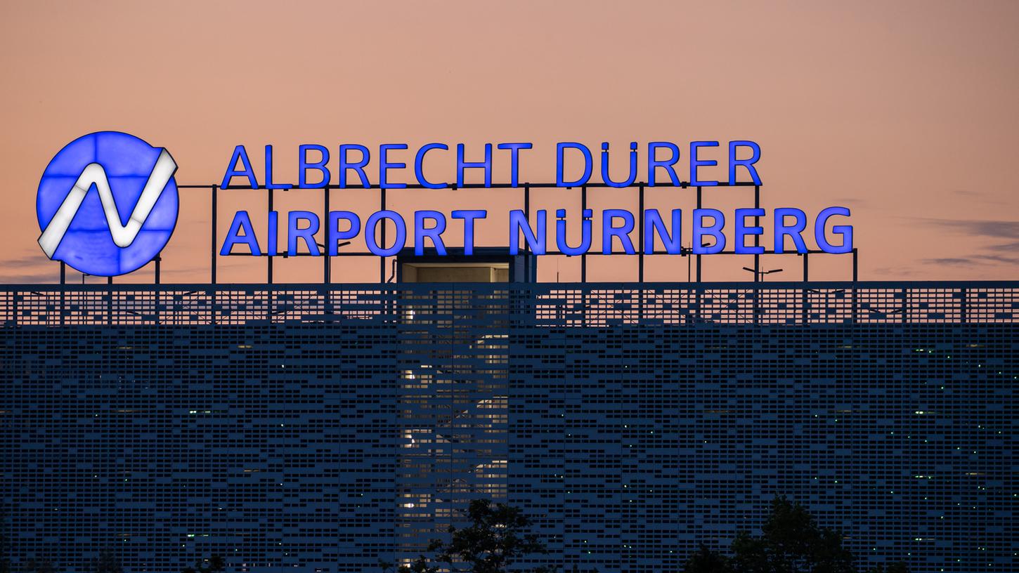 Der Schriftzug "Albrecht Dürer Airport Nürnberg" leuchtet auf dem Dach eines Parkhauses am Flughafen am Abend. Der Schriftzug "Albrecht Dürer Airport Nürnberg" leuchtet auf dem Dach eines Parkhauses am Flughafen am Abend.