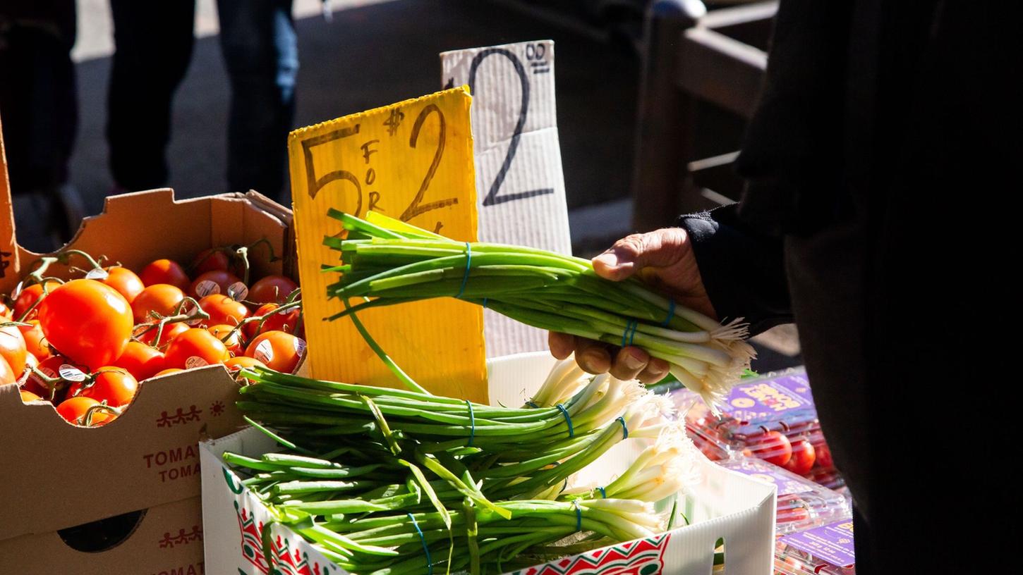 Ein Kunde wählt im New Yorker Stadtteil Brooklyn Gemüse an einem Stand aus. Die Inflation in den USA schwächt sich leicht ab.