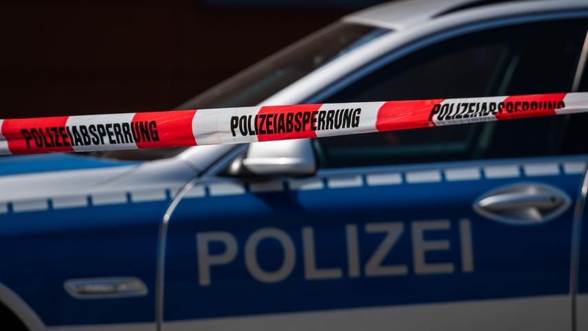 Ein Polizeiauto steht hinter einem Absperrband der Polizei. Ein Polizeiauto steht hinter einem Absperrband der Polizei.