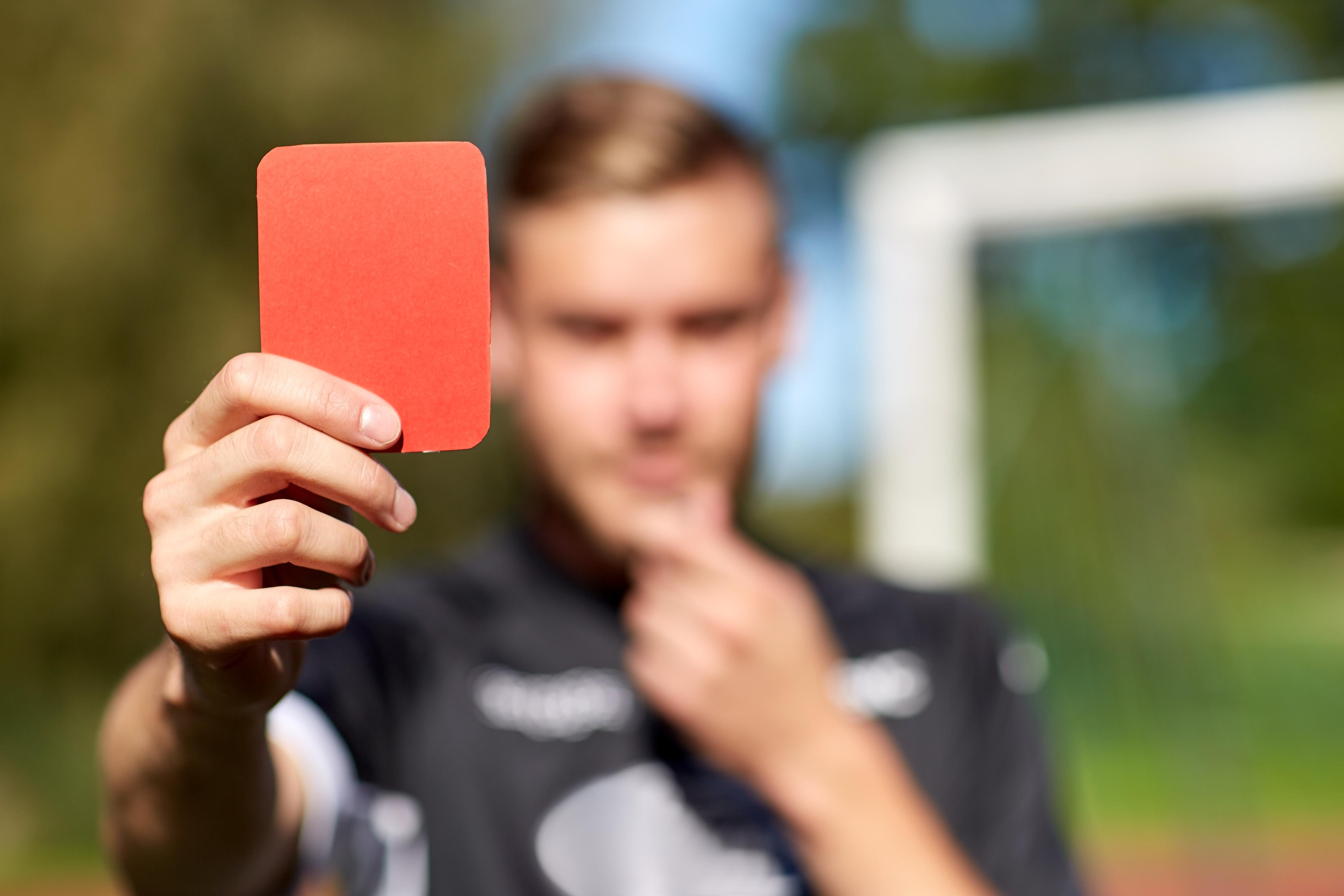 referee hands with red card on football field