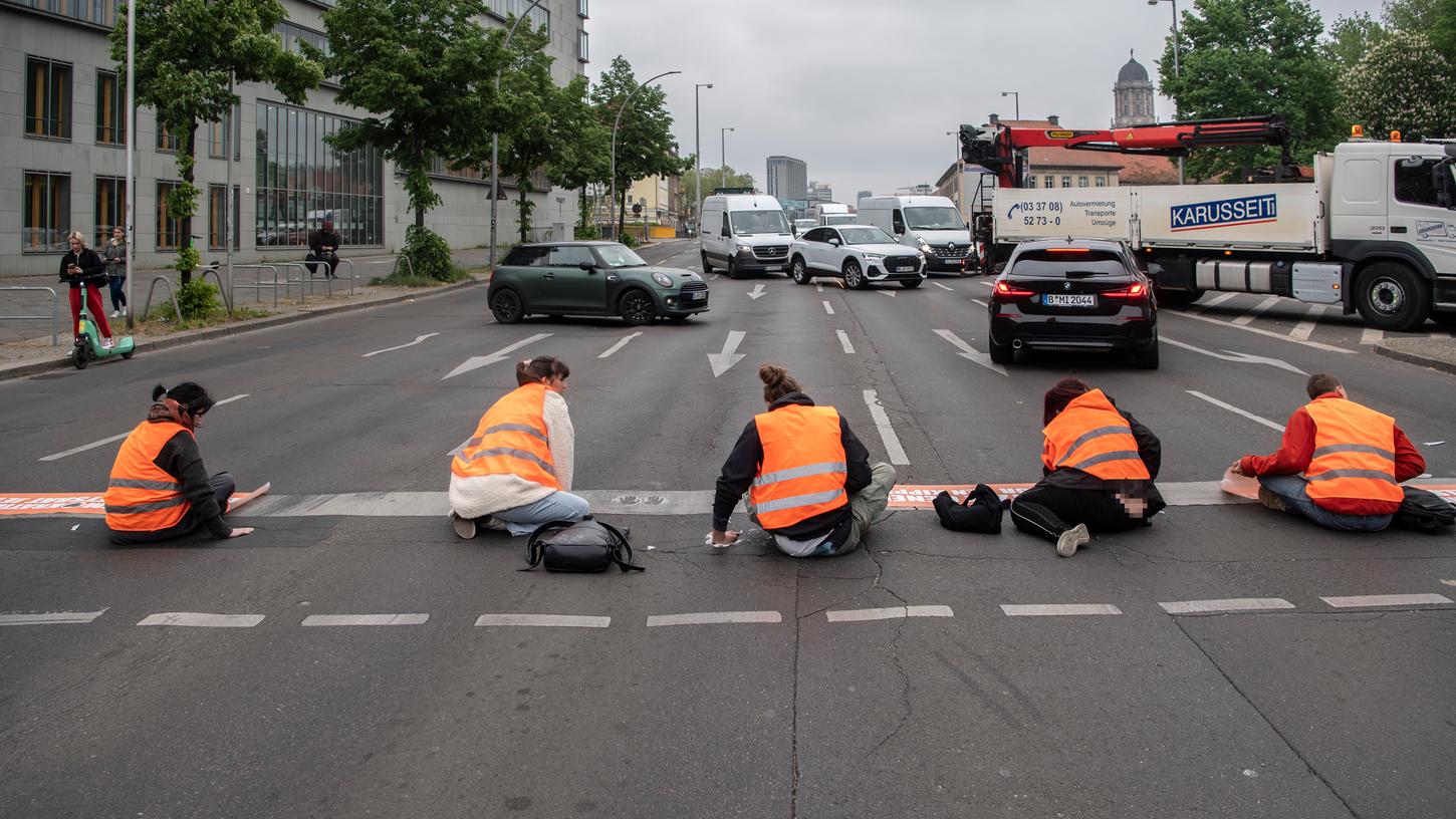 Bei einer Straßenblockade der Letzten Generation sitzen Aktivisten in Berlin am Mühlendamm auf der Straße. Bei diesem Protest nutzten sie auch eine neue Methode, um auf den Klimawandel aufmerksam zu machen.
