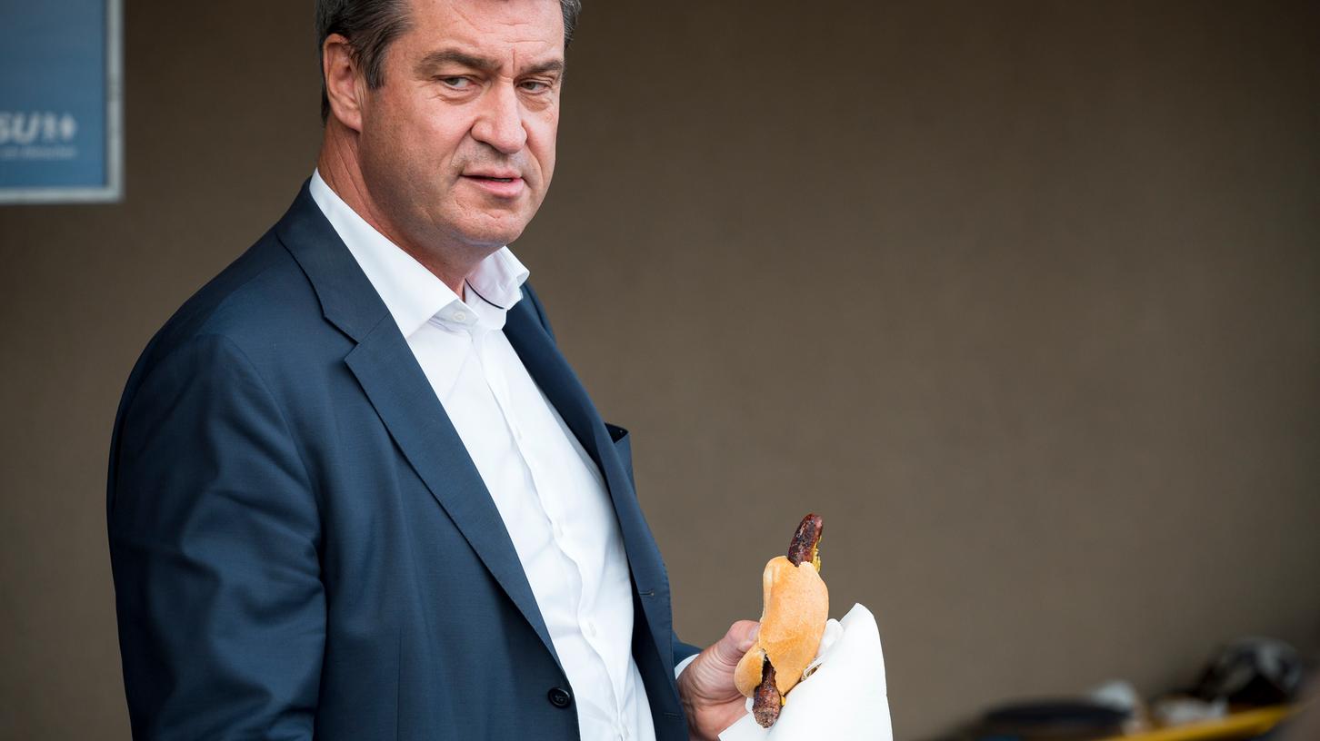 Markus Söder isst ein Bratwurstbrötchen.