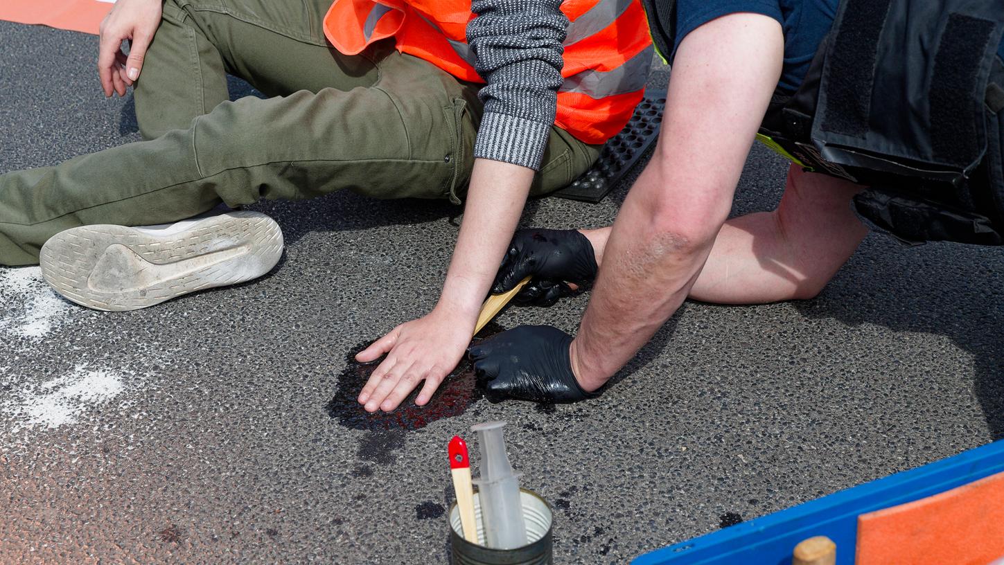Klimakleber auf der Straße des 17. Juni in Berlin. Die Polizei entfernt die festgeklebten Hände der Aktivisten, zum Teil drohen den Aktivisten Haftstrafen.
