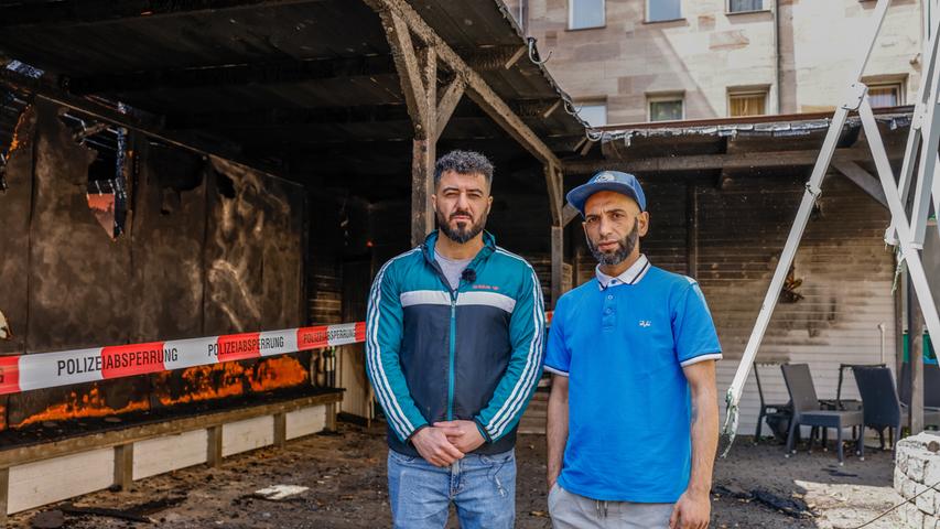 Naschuan Hassan und Efthimios Tsompanis stehen in dem stark in Mitleidenschaft gezogenen Außenbereich ihres Burgerladens.