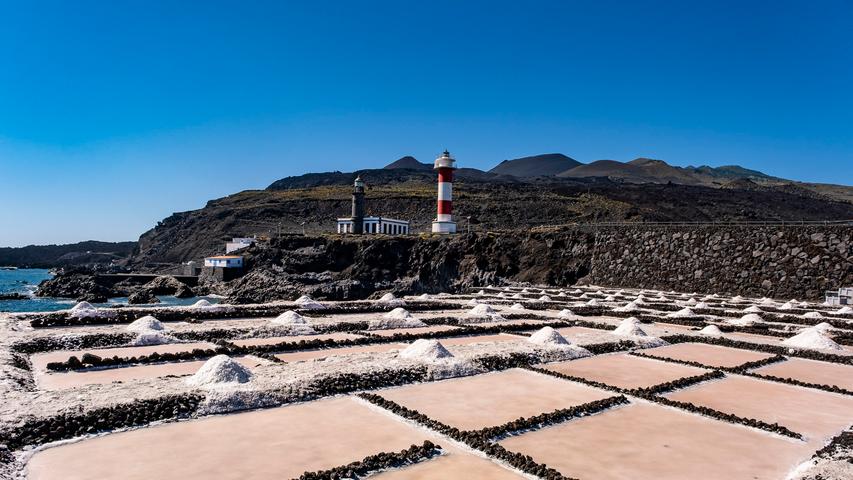 In den Salinas del Fuencaliente an der Südspitze der Insel werden pro Jahr noch 800 Tonnen Salz auf traditionelle Weise geerntet. Von den beiden Leuchttürmen im Hintergrund ist nur der rot-weiß gestreifte in Betrieb, um Schiffe vor den schwarzen Lavaklippen zu warnen.