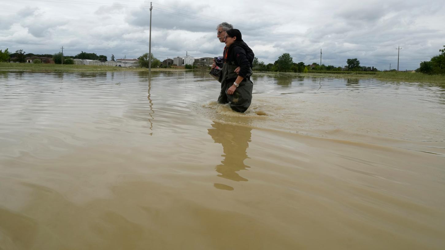 18.05.2023, Italien, Lugo: Ein Paar geht auf einer überfluteten Straße. Nach einer monatelangen Trockenperiode in Norditalien regnete es in den vergangenen Wochen häufig und teils sehr intensiv.