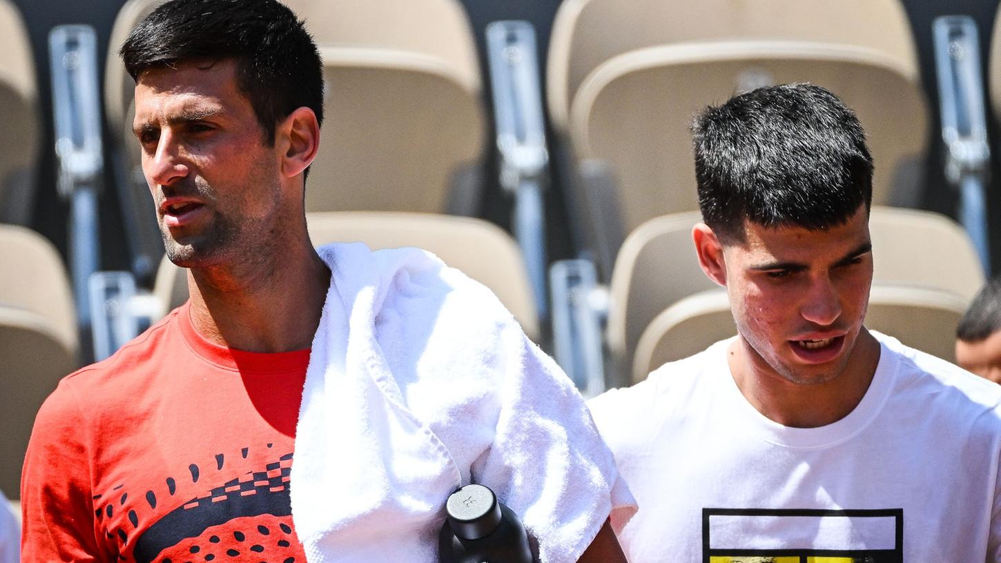 Novak Djokovic (l) aus Serbien und Carlos Alcaraz aus Spanien gehen nebeneinander während einer Trainingseinheit für die French Open 2023.