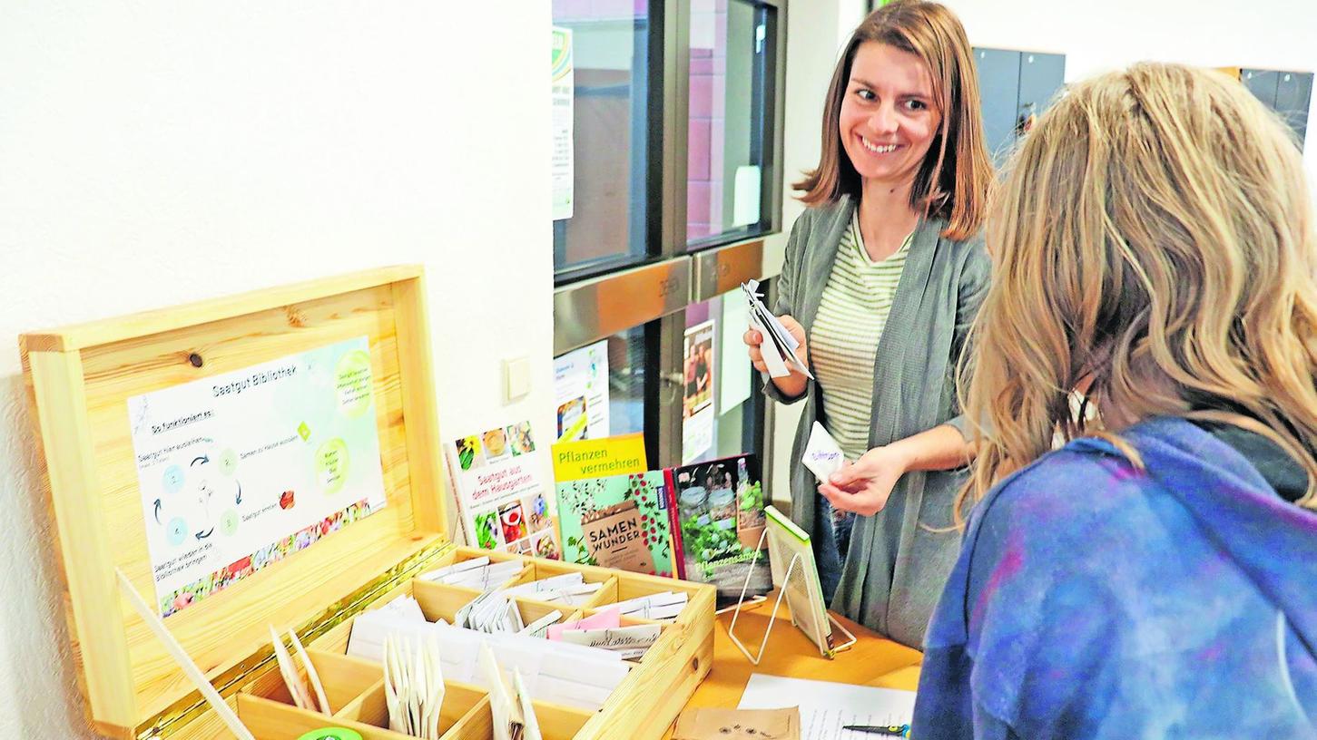 Klima- und Nachhaltigkeitsbeauftragte Sina Mixdorf (im Bild) steht mit Stadtbücherei-Leiterin Edith Backer hinter der Initiative. Die Box in der Bücherei hält für Hobbygärtner Samen verschiedenster Pflanzen bereit.
