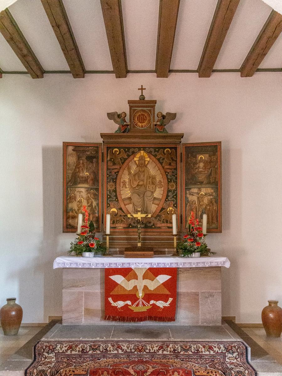 Karl Langes Altar erinnert formal an Flügelaltäre des Mittelalters. Die Bekrönung mit den Engeln ist ein Überbleibsel der alten Kirche an der Laufamholzstraße. 