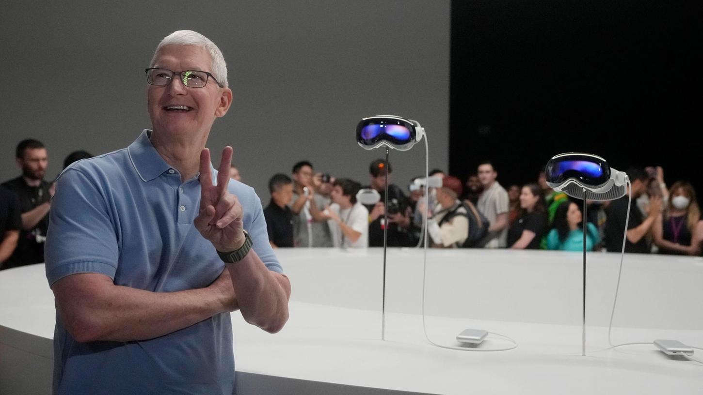 Apple-CEO Tim Cook posiert neben den neuen Vision Pro Headsets auf dem Firmencampus in Cupertino.
