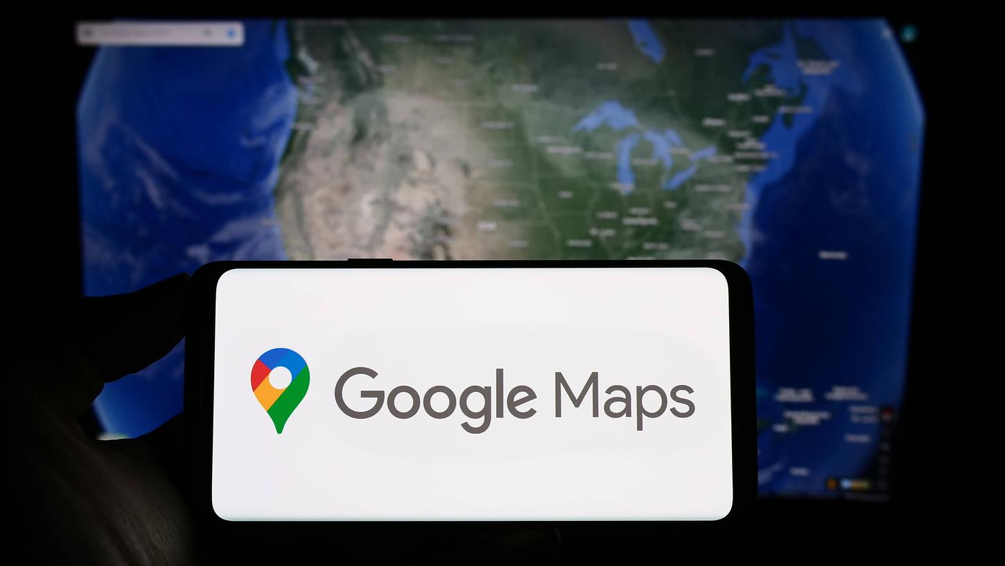Ein Mobiltelefon mit dem Logo der Plattform "Google Maps" auf dem Bildschirm vor einer Webseite. (Symbolbild)