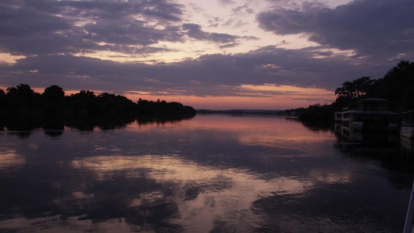 Einen traumhaften Sonnenaufgang erleben Touristen am Sambesi, bevor das Wasser die Viktoriafälle hinabrauscht. 