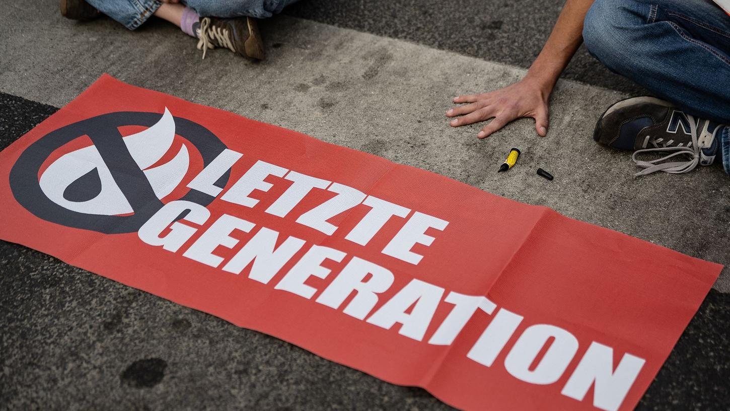 Ein Aktivist der Gruppe Letzte Generation blockiert eine Kreuzung.