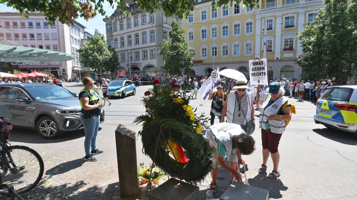 Teilnehmerinnen einer Demonstration gegen eine Kundgebung der AfD stehen an einer Gedenkstele zum Gedenken an die Opfer einer Messerattacke von 2021 nahe des Tatortes.