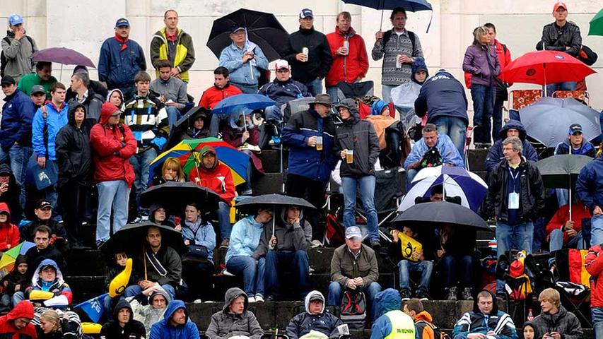 Den hartgesottenen Fans macht der Regen wenig aus, sie schützen sich mit Schirmen, Mützen und Tüten.