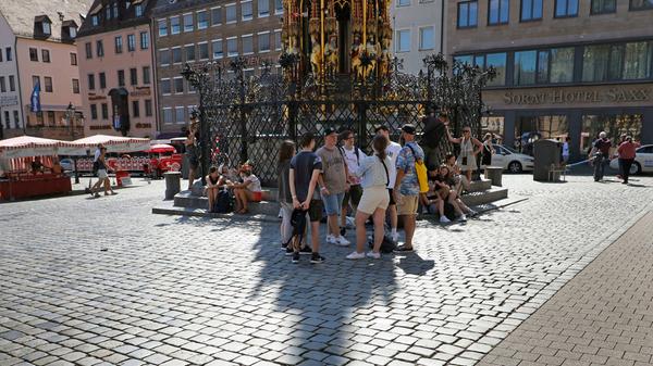 Jeder Schutz vor der Sonne ist willkommen. Am Hauptmarkt nutzen junge Leute den Schatten, den der Schöne Brunnen wirft.