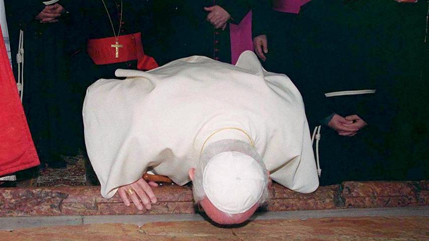 Der heilige Vater auf heiligem Boden. Überall wo Papst Johannes Paul II. zum ersten Mal landete, küsste er den Erdboden den er betrat um das Land zu segnen. Im Jahr 2000, in Jerusalem, küsst er auf diesem Bild den Boden der Grabeskirche, in der Jesus begraben worden sein soll.