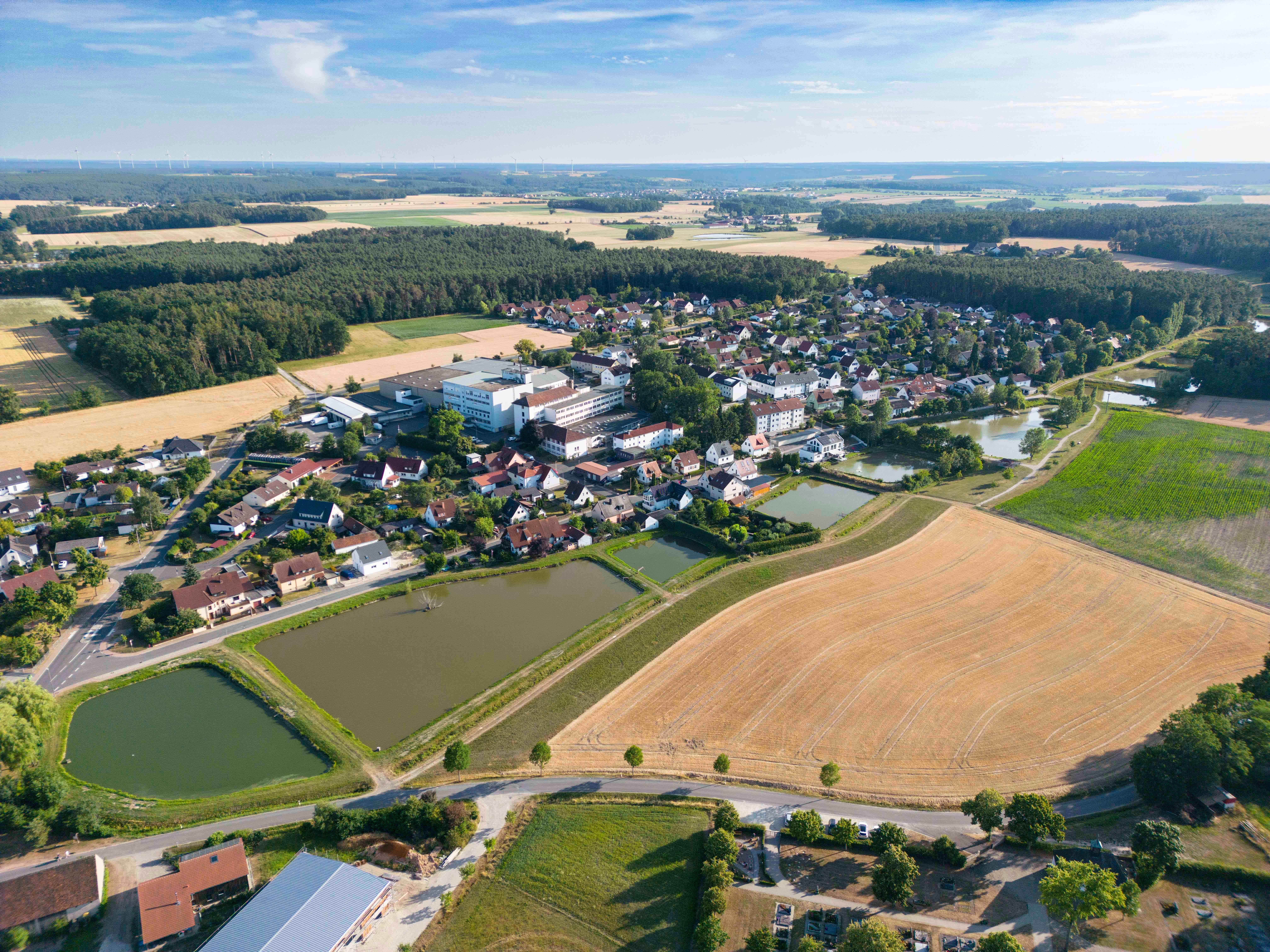 Oberreichenbach mit der Weiherkette ganz am Ortsrand. Das große Gebäude ist eine alter Industriebau, in dem früher die Textil-Firma Seeland produzierte.
