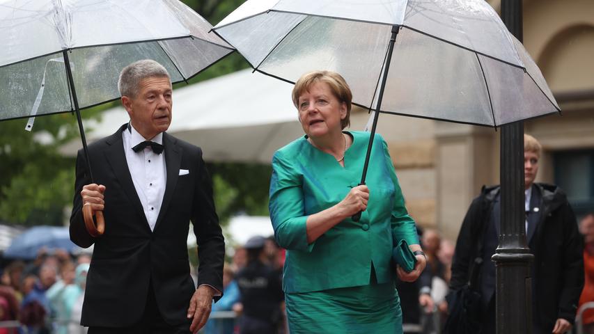 Gut gelaunt trotz Regens hat sich die frühere Bundeskanzlerin Angela Merkel beim Auftakt der Bayreuther Festspiele gezeigt. In einem grün-türkis-schimmernden zweiteiligen Ensemble besuchte sie mit ihrem Mann Joachim Sauer die Premiere von "Parsifal".