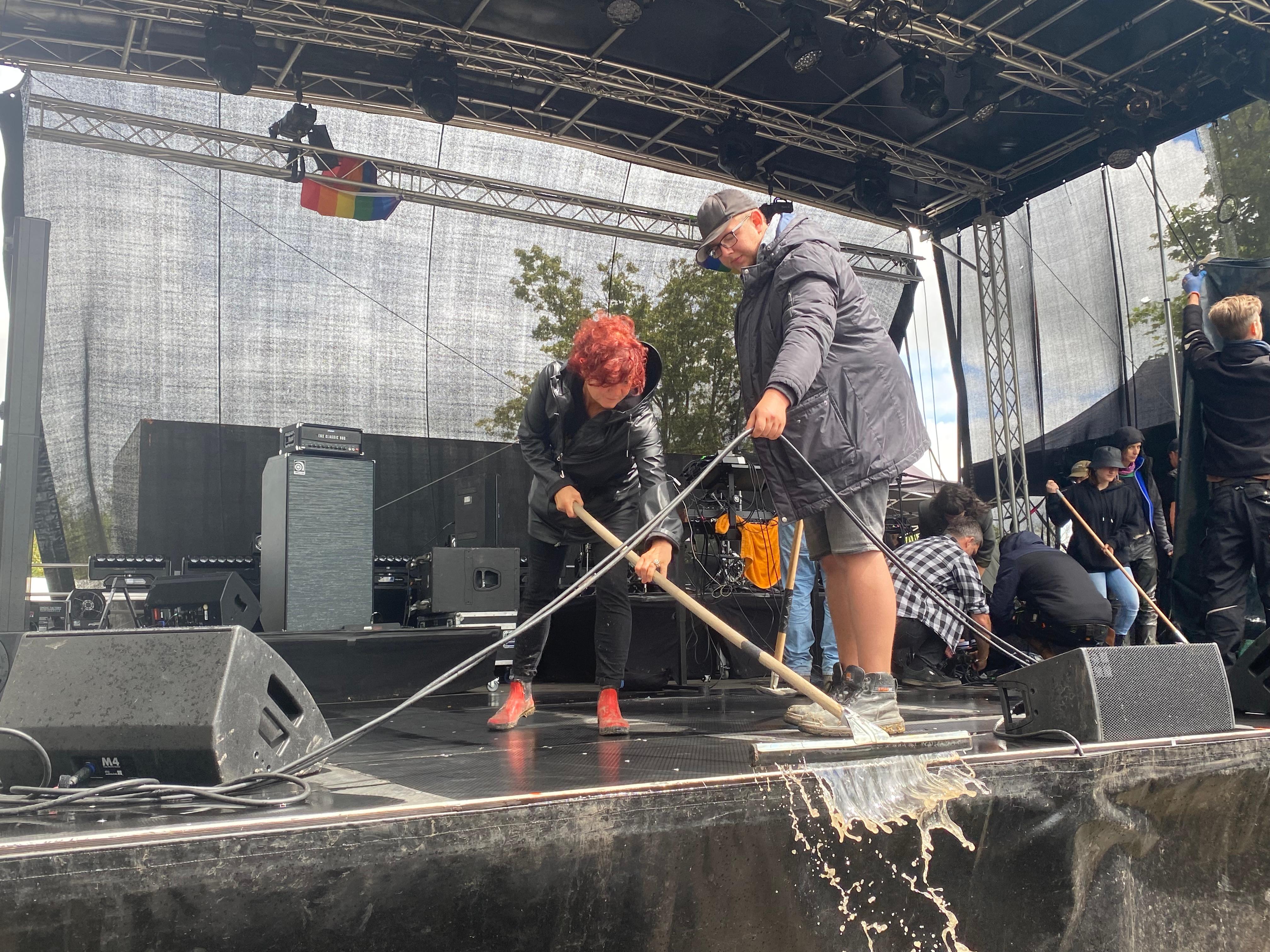 Auf der Bühne sammelte sich das Wasser, das Helferinnen und Helfer unterdessen von der Bühne kehrten.