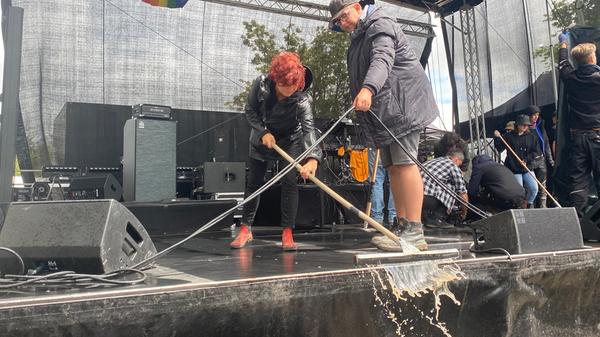 Auf der Bühne sammelte sich das Wasser, das Helferinnen und Helfer unterdessen von der Bühne kehrten.
