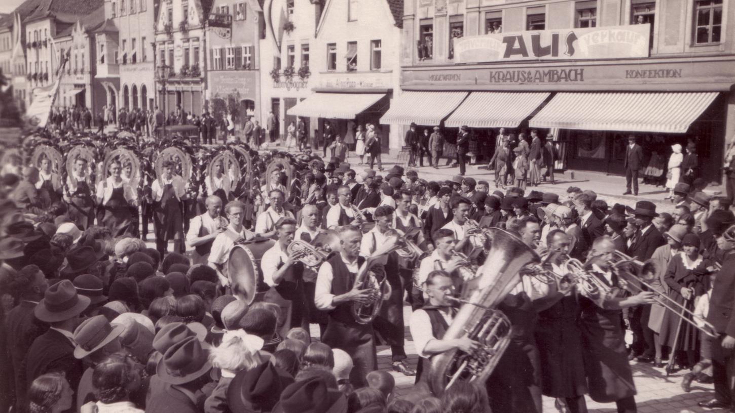 Dicht an dicht stehen die Menschen am Oberen Markt, die Herren trotz Hitze mit Hut: Der Volksfestzug, voran die Blaskapelle, dann die Schäffler, zieht zum Festplatz.