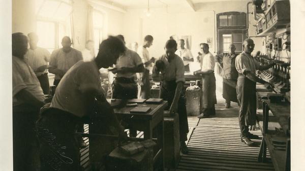 Die Urheber des Beinamens "Goldschlägerstadt": Eine Schwabacher Werkstatt mit Goldschlägern um das Jahr 1900. Links die Goldschläger an ihren Schlagsteinen, rechts Formenpresser. In die Formen (Bücher) wurden Goldfolien zum Schlagen eingelegt. Sie mussten unter den Pressen getrocknet werden.