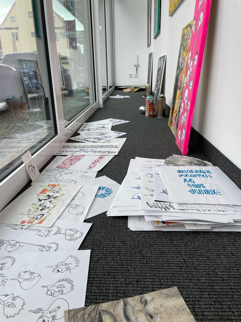 Skizzen verteilt der Künstler auf dem Teppichboden im Kunstfenster. Skizzen verteilt der Künstler auf dem Teppichboden im Kunstfenster.