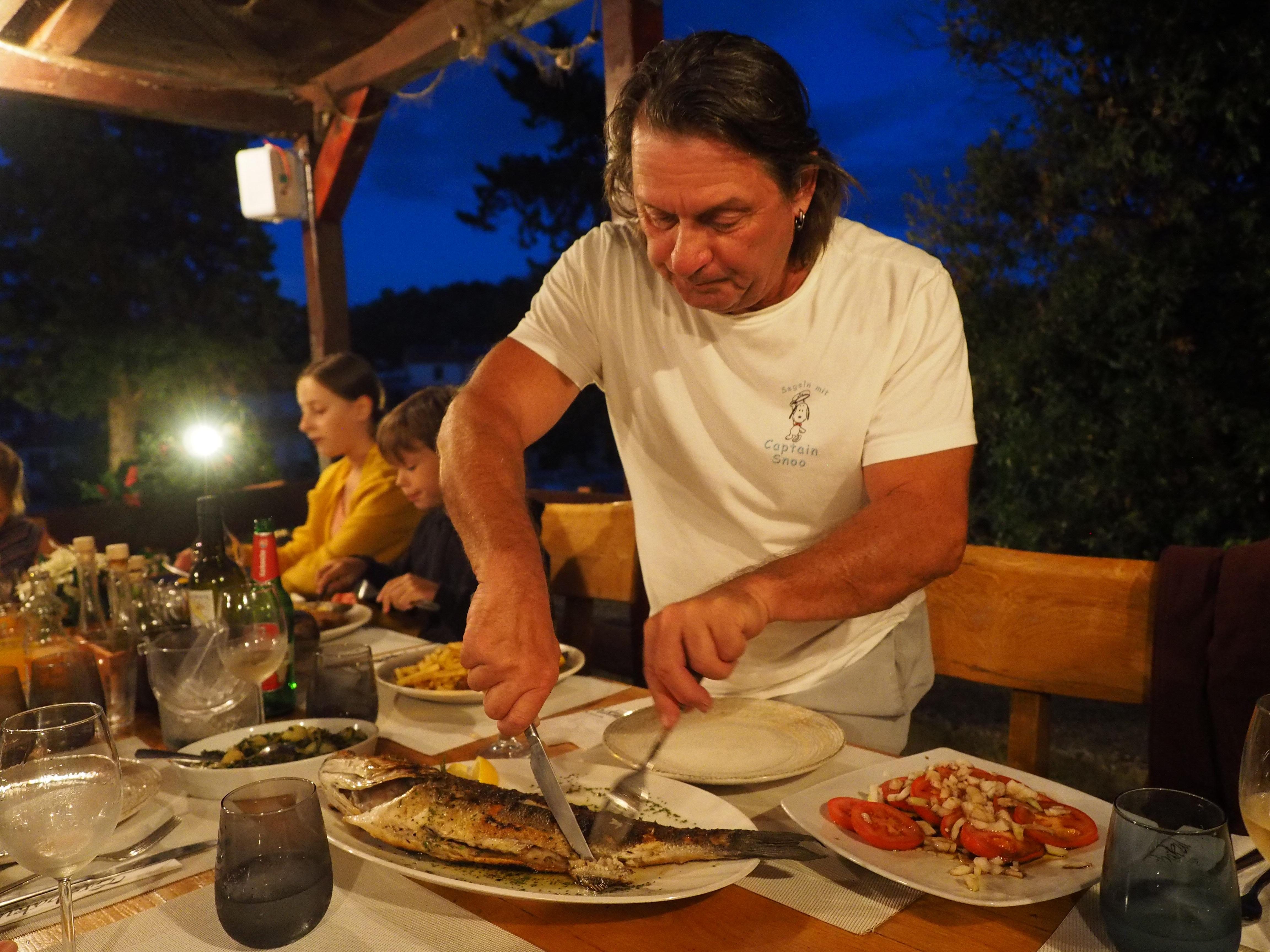 Käpt'n Snoo filetiert einen frisch gegrillten Fisch.
