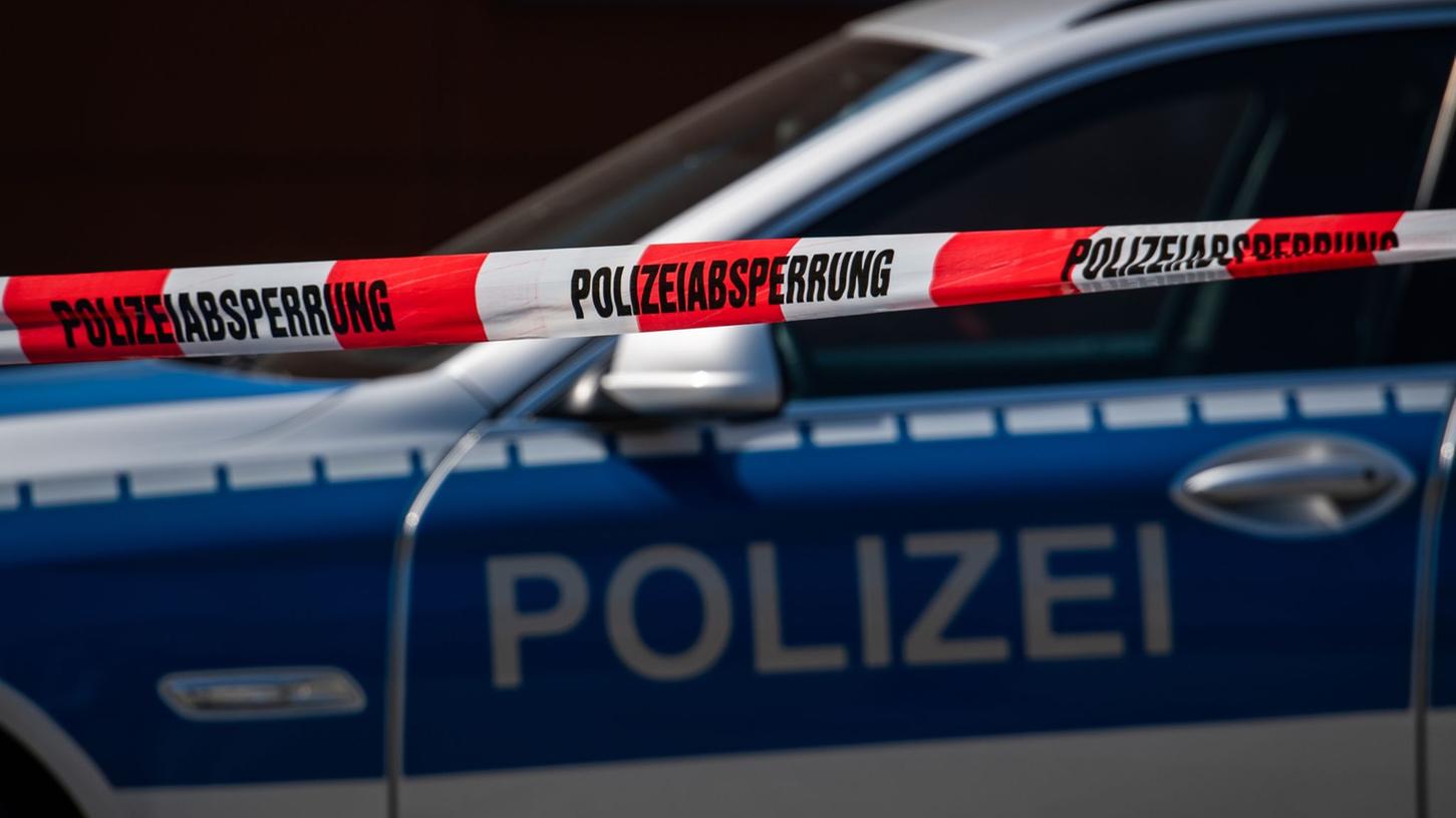 Ein Polizeiauto steht hinter einem Absperrband der Polizei. Ein Polizeiauto steht hinter einem Absperrband der Polizei.