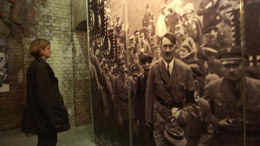 Eine Frau betrachtet im Dokumenationszentrum Reichsparteitagsgelände in Nürnberg ein großformatiges Foto von Adolf Hitler. 
