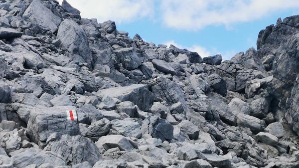 Rot-weiße Wegmarkierung, hier am Einstieg zum Orgelpass am Tinzerhorn im hochalpinen Geröll.