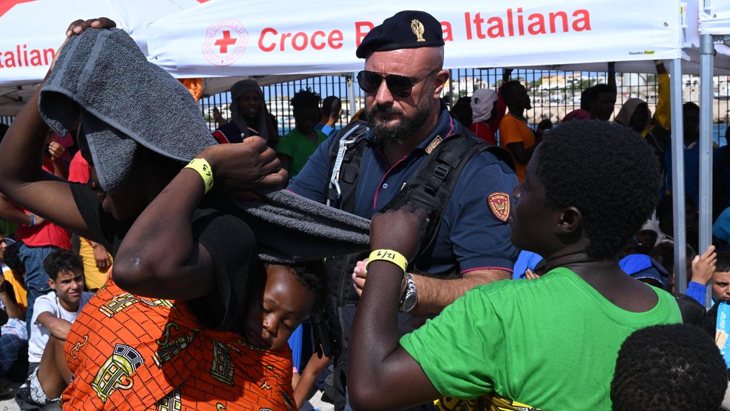 Auf Lampedusa gestrandete Migranten warten, um auf ein Schiff zu gelangen, das sie zum italienischen Festland bringen soll. 