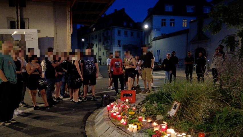 Nach einer tödlichen Messerstecherei in Würzburg haben sich zahlreiche Freunde und Bekannte des Opfers am Kreisverkehr des Haugerkirchplatzes versammelt, um Blumen und Kerzen niederzulegen.