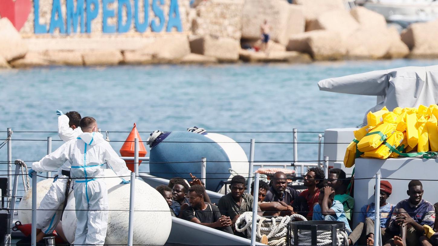 Gerettete Migranten im Hafen der italienischen Insel Lampedusa. Die Ankunft Tausender Bootsmigranten in kurzer Zeit hat die Insel an ihre Grenzen gebracht. Gerettete Migranten im Hafen der italienischen Insel Lampedusa. Die Ankunft Tausender Bootsmigranten in kurzer Zeit hat die Insel an ihre Grenzen gebracht.