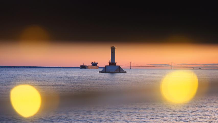Abendstimmung vor Mackinac Island mit Leuchtturm und Frachter.