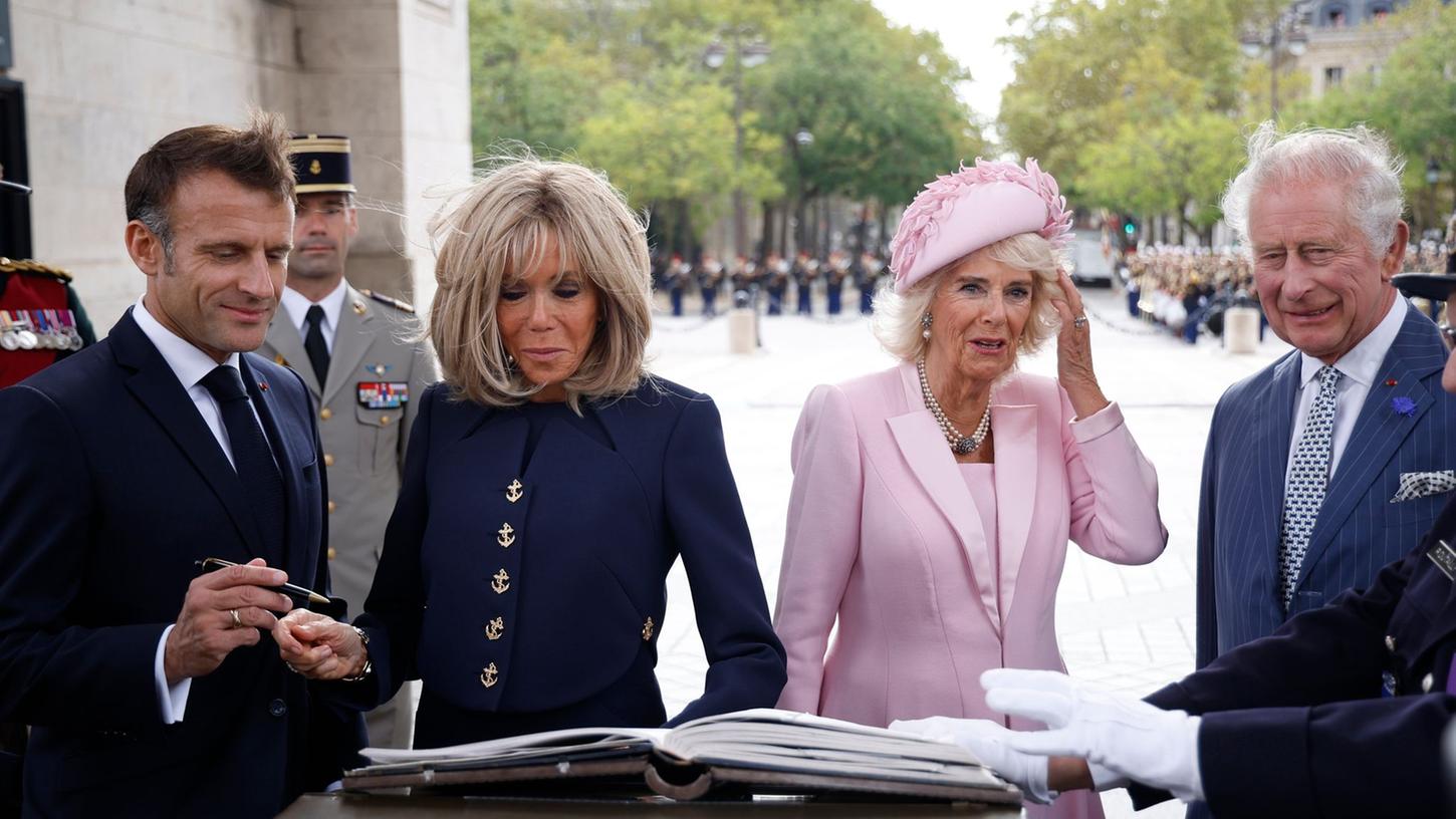 Präsident Emmanuel Macron (l-r) und und seine Ehefrau Brigitte Macron sowie Königin Camilla und König Charles III. von Großbritannien tragen sich während einer Zeremonie am Triumphbogen in Paris ins Goldene Buch ein.