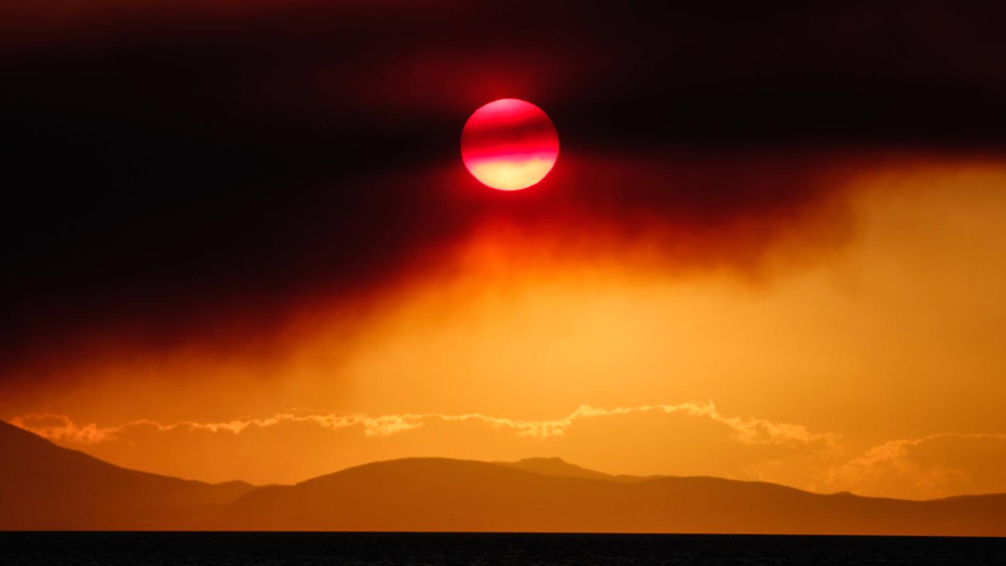 Nein, hier bahnt sich keine Sonnenfinsternis an: Der Rauch eines Waldbrandes sorgt für ein bizarres Farbenspiel am Himmel über Griechenland.