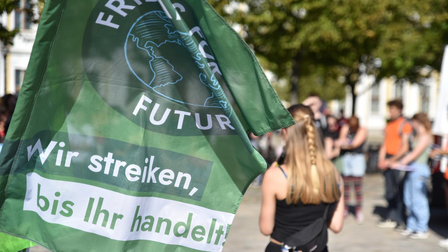 Eine Rednerin spricht zum "Klimastreik" von Fridays for Future auf dem Domplatz in Magdeburg. Im Vordergrund ist eine Flagge der Klimaaktivisten (Symbolbild).