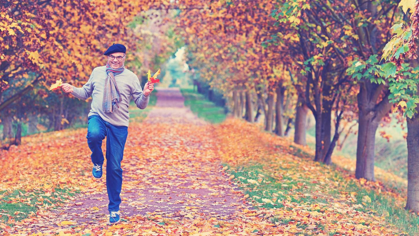 Manche macht schon das Hüpfen durchs Herbstlaub fröhlich. Am glücklichsten - so zeigt die Forschung -  sind junge und alte Menschen. 